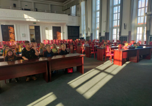 Uczniowie biorą czynny udział w debacie w sali obrad Rady Miejskiej.