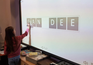 Uczennica porządkuje litery hasła na tablicy interaktywne