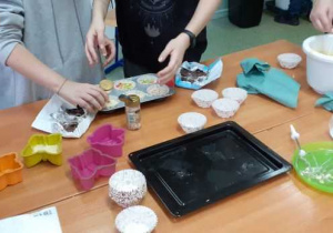 Dzieci wlewają ciasto do mufinkowych foremek.