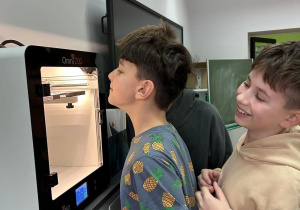 Dwóch uczniów przed drukarką 3D