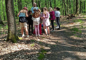 Uczniowie klasy IIb z edukatorem w środku lasu