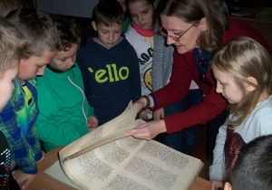 Uczniowie oglądają XIX wieczne wpisy w księgach parafialnych.
