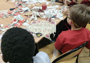 Uczniowie za stołem pełnym kolorowych materiałów plastycznych