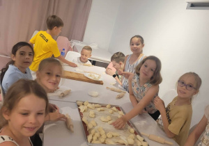Uczniowie przy stole podczas lepienia pierogów