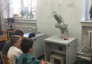 Uczniowie sterują robotem przemysłowym.